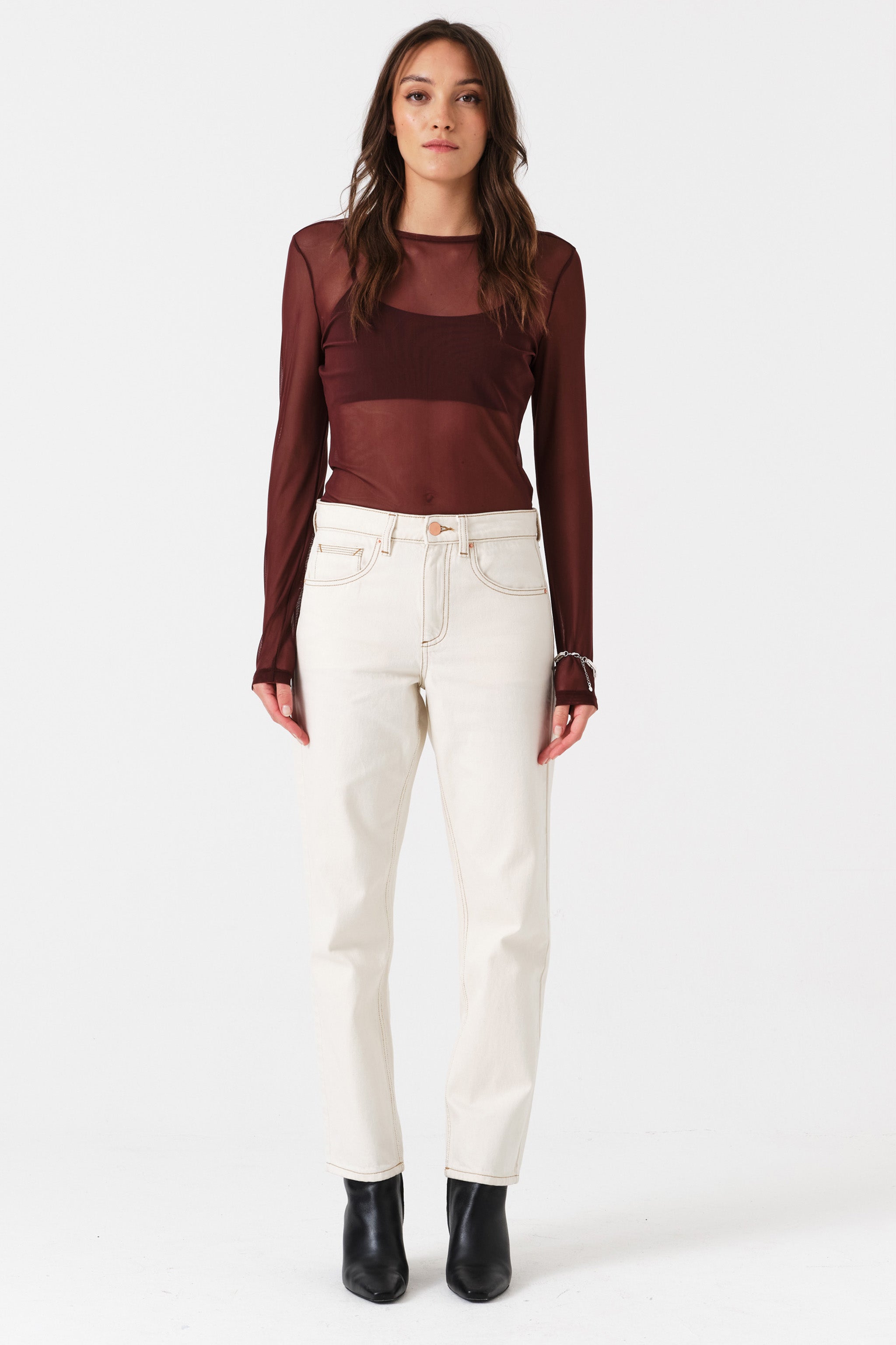 Woman wearing off white straight leg jeans and a brown shirt on a white background