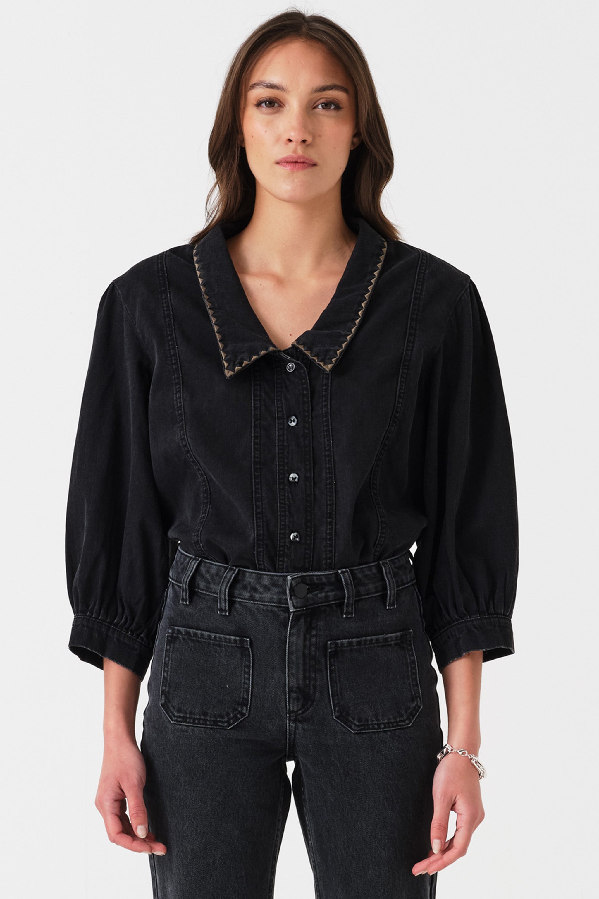 Woman wearing a black denim shirt with oversized collar on a white background