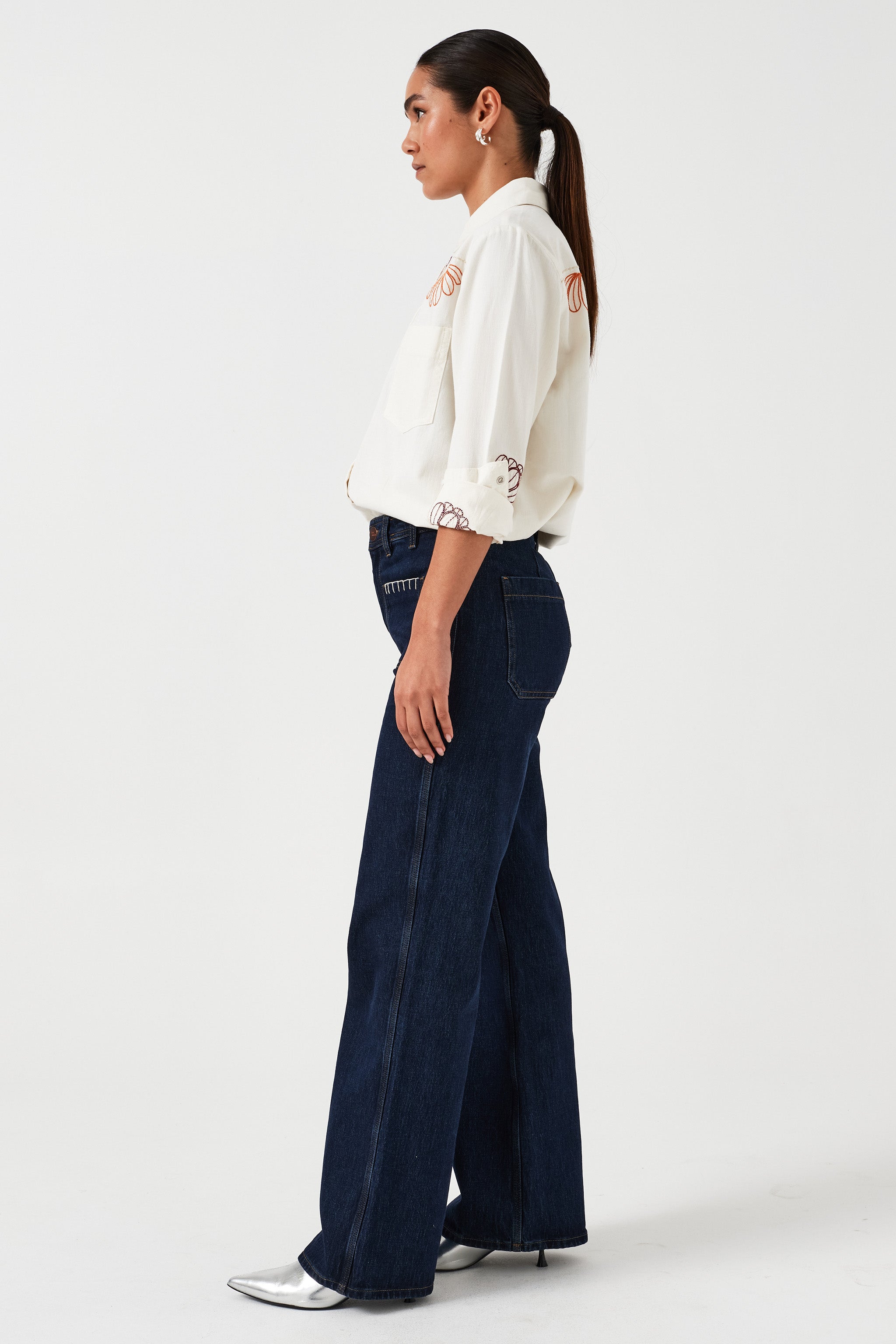 Woman standing showing the side of a pair of dark vintage wide-leg jeans with high-rise waist.